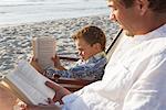 Father and Son Reading on Beach, Majorca, Spain