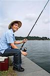 Man sitting on cooler, fishing with fishing pole