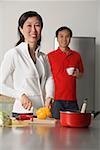 Reife Frau in der Küche bereiten ein Essen Mann stand hinter ihr, beide Blick in die Kamera