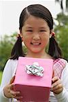 Girl holding pink wrapped gift box, smiling