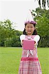 Girl with party hat holding pink gift box towards camera