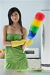 woman in kitchen, holding feather duster, thinking, cleaning