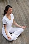 Woman meditating on porch, eyes closed, in yoga OM posture.