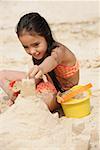 Château de sable de construction jeune fille sur la plage