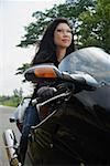 Mature woman riding motorcycle, wearing sunglasses