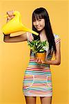 Jeune femme arroser la plante avec l'arrosoir jaune vif
