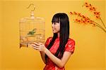 Young woman holding lovebird in bird cage