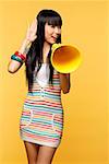 Young woman talking through yellow megaphone, hand to ear