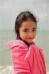 Young girl on beach wrapped in pink towel