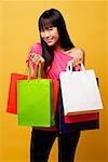 Jeune femme tenant des sacs à provisions souriant à la caméra