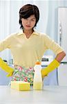 Woman in kitchen with hands on hip, cleaning detergent and sponge on kitchen counter