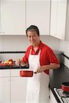 Mann in der Küche Kochen mit Topf, Blick in die Kamera Schürze tragen
