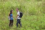 Homme et femme de randonnée à travers les hautes herbes, nature, plein air