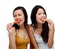 Two young women biting into Popsicle, looking at camera