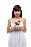 Young woman wearing white dress and holing small plant