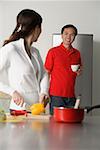Reife Frau in der Küche Vorbereiten einer Mahlzeit, um hinter ihr stehenden Mannes aussehen drehen