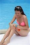 Frau trägt Rosa Bikini, sitzen am Schwimmbad, Sonnencreme anwenden