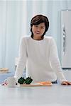 Woman in kitchen, smiling at camera