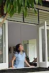 Woman at home, standing by window looking out