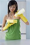 woman in kitchen, squeezing soap onto sponge, cleaning