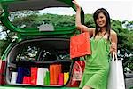 A young woman puts her shopping in the back of a car
