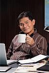 A man having a drink while working at his desk