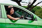 A young woman drives a green car