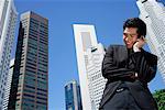 A man talks on his cellphone with skyscrapers in the background