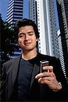 A man checks his phone while outdoors in the city