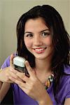A teenage girl smiles at the camera as she uses her cellphone