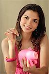 A teenage girl smiles at the camera as she puts a coin in a piggy bank