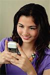 A teenage girl smiles as she uses her cellphone