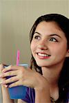 A teenage girl smiles as she has a drink