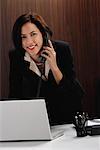 A woman looks at the camera while she talks on the phone at work