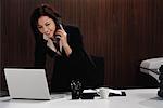 Eine Frau am Telefon spricht, während sie an ihrem Schreibtisch ist