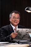 Ein Mann in die Kamera lächelt, als er die Zeitung am Arbeitsplatz liest