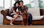 A young couple with a dog look at the camera