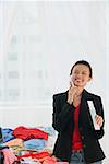 Young woman packing clothes while on the phone