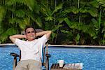 Man relaxing in deck chair by the pool