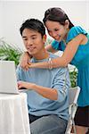 Young woman leaning on shoulder of man at the computer