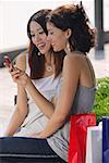 Women sitting on bench, looking at mobile phone