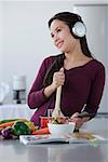 Young woman cooking while listening to music