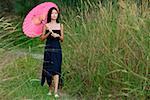 Woman walking in long grass with parasol