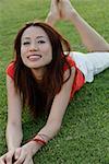 Woman lying in park, smiling at camera