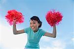 Young woman cheerleading with pom poms