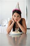 Jeune femme avec gâteau d'anniversaire à la recherche s'ennuie