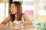 Young woman holding mug, looking away