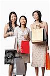 Trois jeunes femmes tenant des sacs à provisions