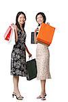 Two young women carrying shopping bags, looking at camera