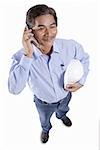 Mature man holding construction hat, using mobile phone